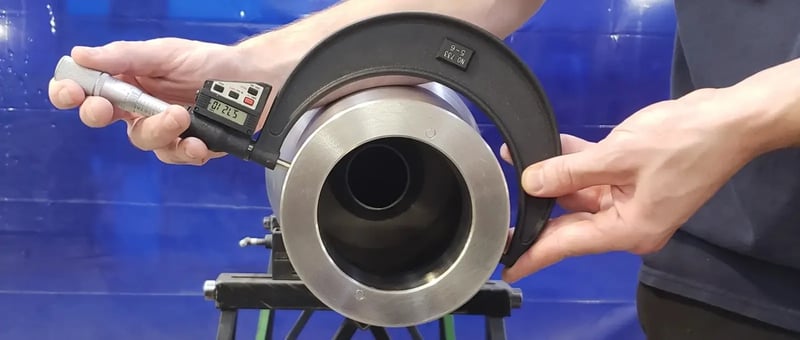 A technician uses a digital micrometer to measure critical dimensions of a decanter centrifuge component.