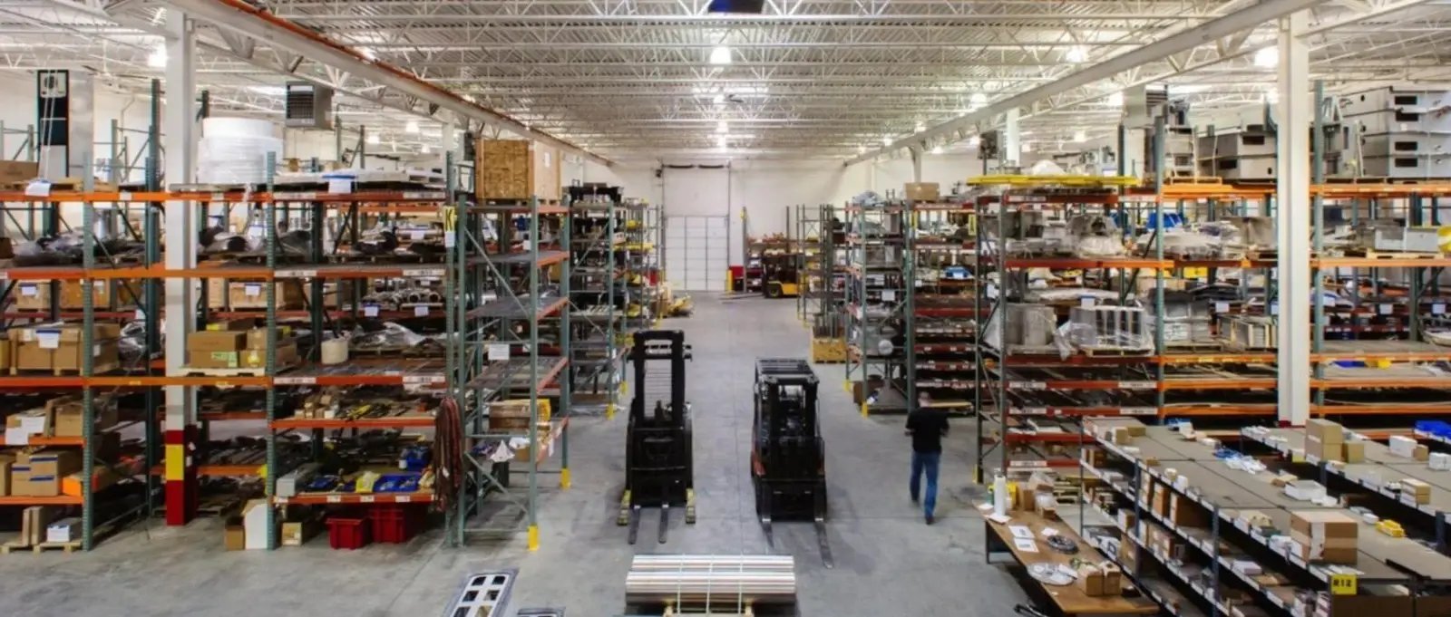 A spacious and organized decanter centrifuge repair facility with forklifts and stocked parts shelves.