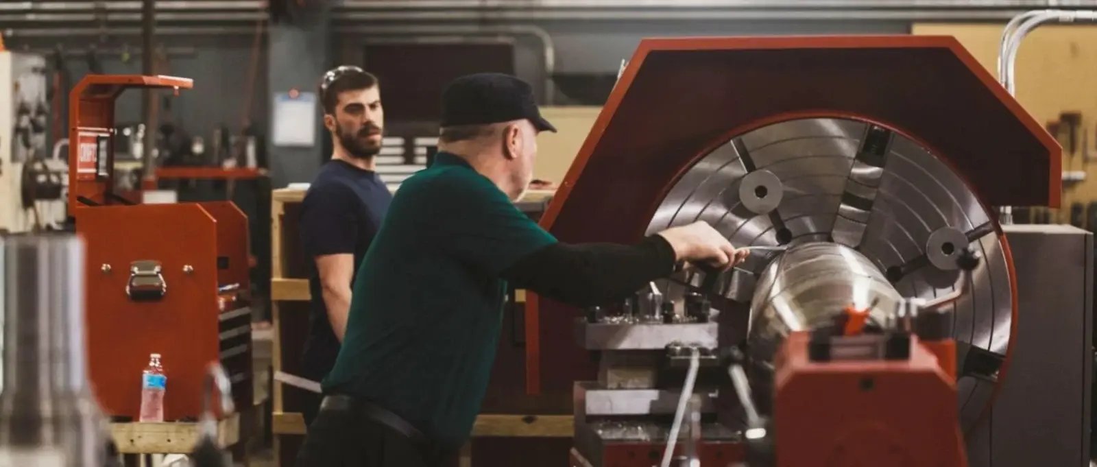 Two technicians machining a component in a decanter centrifuge repair facility.
