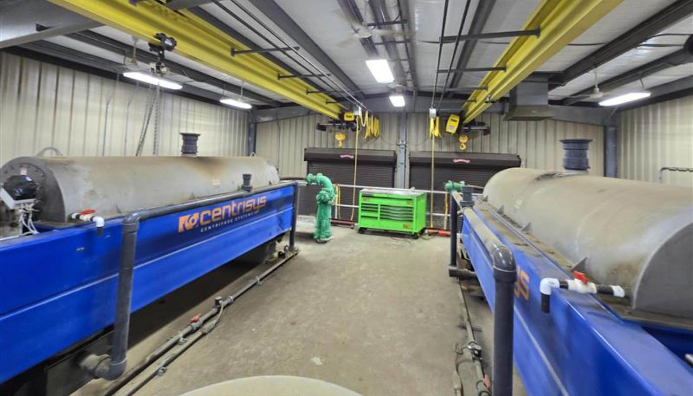Two decanter centrifuges shown in a facility with a concrete floor.