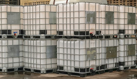 A stack of polymer bins set outside on pavement.